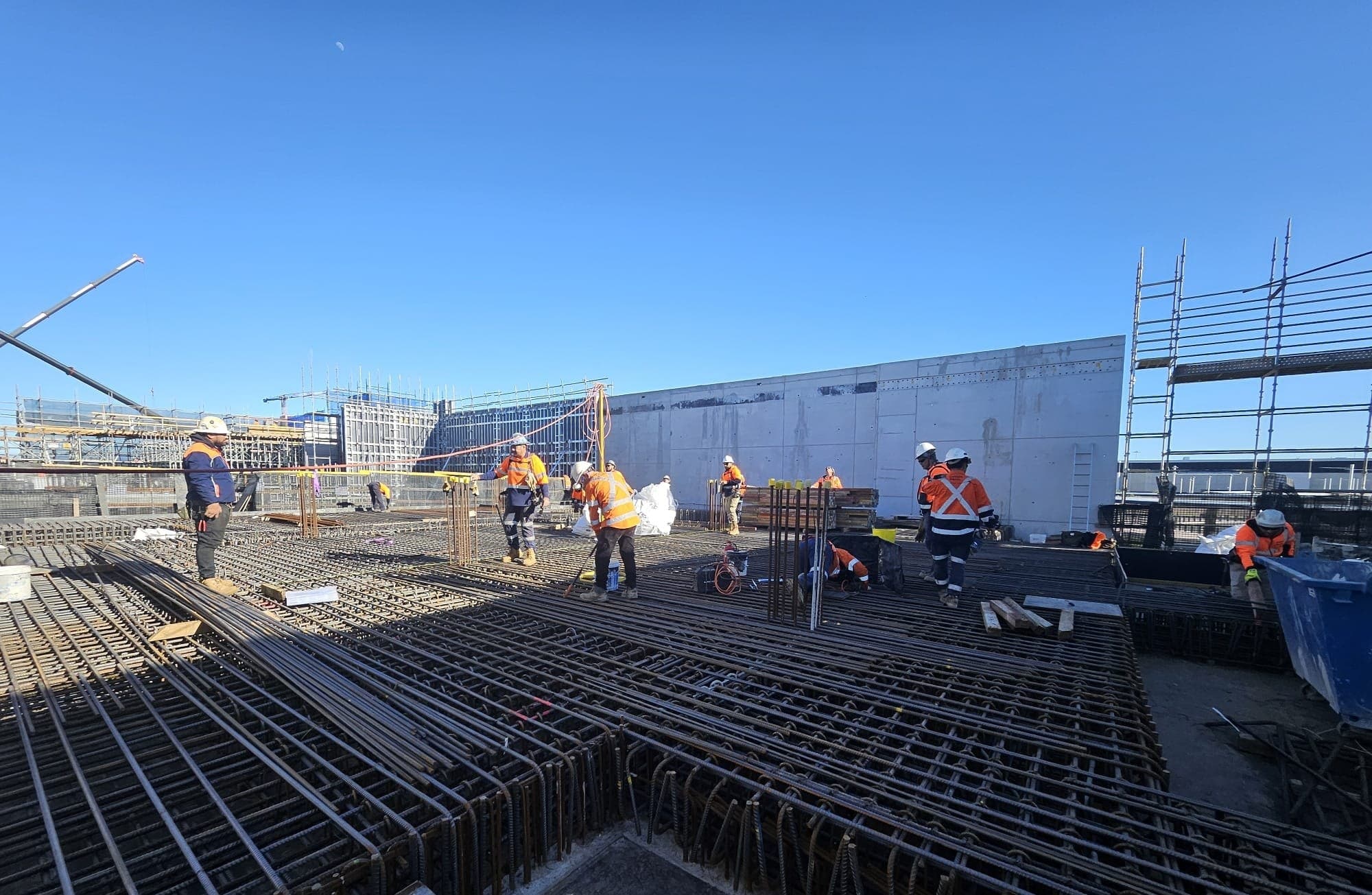 A crew working across a deck of reinforcement at the scale of the pour